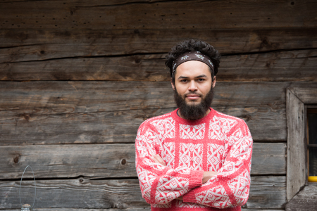 portrait of young hipster,  man with beard in front of old vintage wooden house