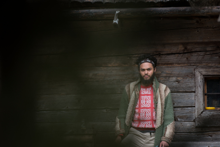 portrait of young hipster,  man with beard in front of old vintage wooden houseの写真素材