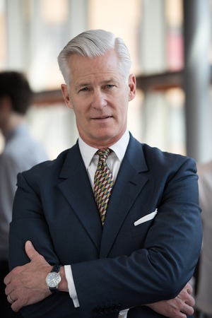portrait of handsome senior business man with grey hait at modern bright office interiorの写真素材