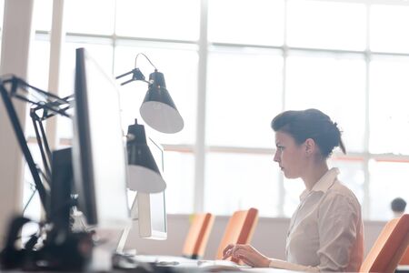business woman working on desktop computer at modern startup officeの写真素材