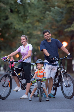 portrait of happy young family with bicycles in park at nightの写真素材
