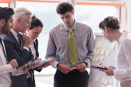young startup businessman making presentation of project to senior investior, group of business people taking notes and make plans on white  flip board and tablet computerの写真素材