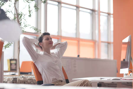happy young business woman relaxing and geting insiration while working on desktop computer at modern bright  starup office interiorの写真素材