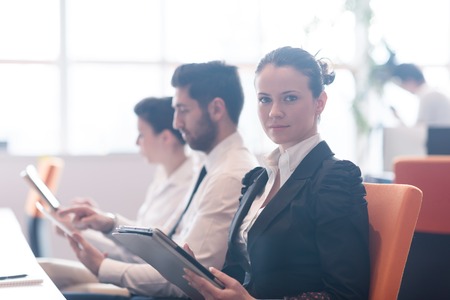 business woman on meeting usineg tablet computer, blured group of people in background at  modern...