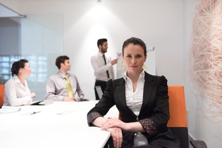 young business woman on meeting usineg laptop computer, blured group of people in background at ...