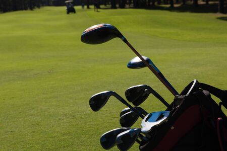 close up of golf bag on course with  club and ball in front at beautiful sunriseの写真素材