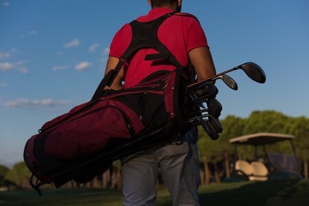 close up of golfers back while carrying  golf bag  and walking at course to next holeの写真素材