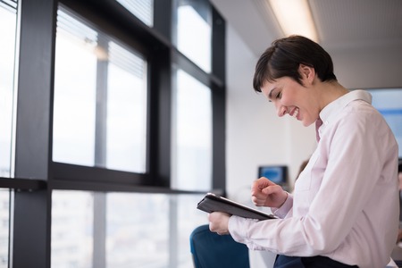 business woman on meeting usineg tablet computer, blured group of people in background at  modern bright startup office interiorの写真素材