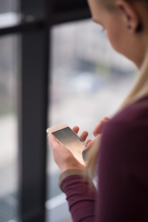 business woman at office using smart phone to check internet and type messagesの写真素材