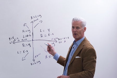 portrait of confident teacher solving problems on whiteboard in classroomの写真素材