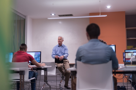 handsome mature teacher and students in computer lab classroom