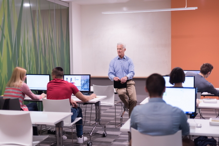 handsome mature teacher and students in computer lab classroom