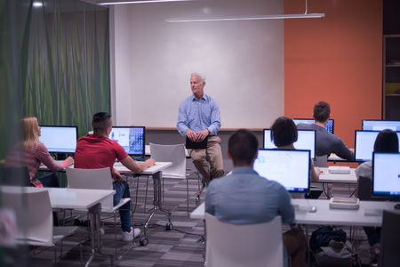handsome mature teacher and students in computer lab classroom