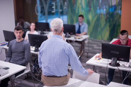 handsome mature teacher and students in computer lab classroom
