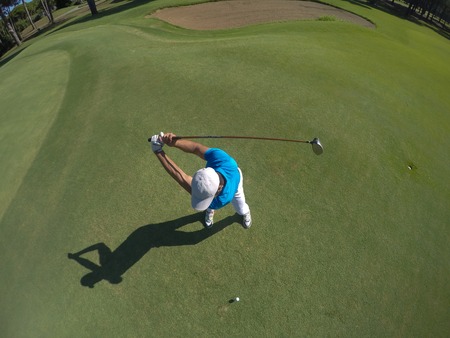 top view of golf player hitting shot with club on course at beautiful morningの写真素材