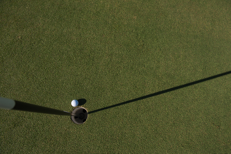 top view of golf ball on edge of course hole representing achivement and success business conceptの写真素材