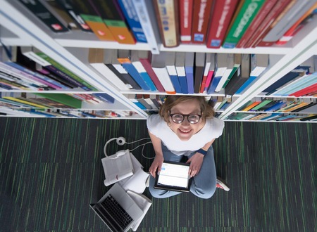 female student study in library using tablet and searching internet while  Listening music and...