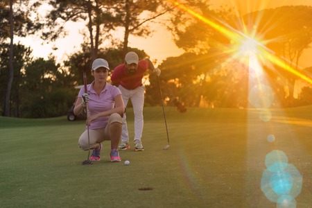 portrait of happy young  couple on golf course with beautiful sunset in backgroundの写真素材