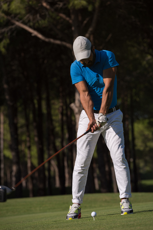golf player hitting shot with club on course at beautiful morningの写真素材