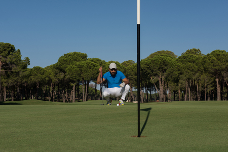 golf player aiming shot with club on course at beautiful sunny dayの写真素材