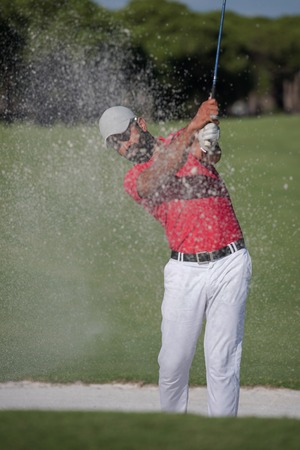 golf player shot ball from sand bunker at courseの写真素材