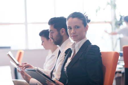 business woman on meeting usineg tablet computer, blured group of people in background at  modern bright startup office interiorの写真素材