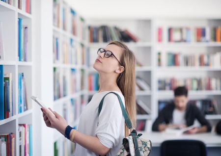 smart looking famale student girl  in collage school library selecting book to readの写真素材