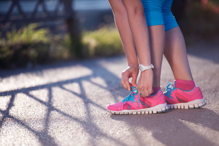 Closeup of jogging woman tying running shoeの写真素材
