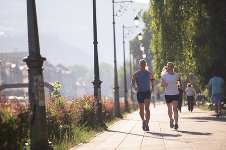 healthy mature couple jogging in the city  at early morning with sunrise in background