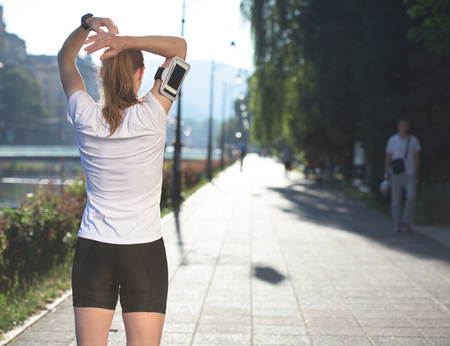 Fit blonde runner   woman warming up and stretching before morning joggingの写真素材