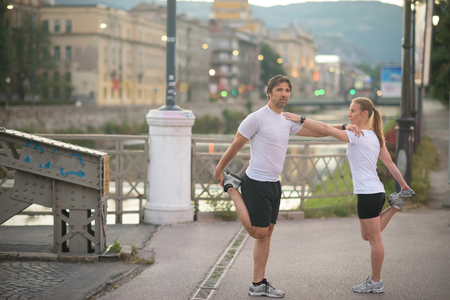 jogging couple warming up and stretching before morning running in the cityの写真素材