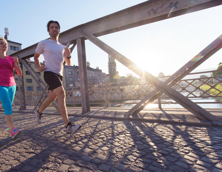 healthy mature couple jogging in the city  at early morning with sunrise in backgroundの写真素材