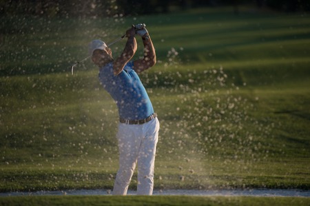 golfer shot ball from sand bunker at golf course with beautiful sunset in backgroundの写真素材