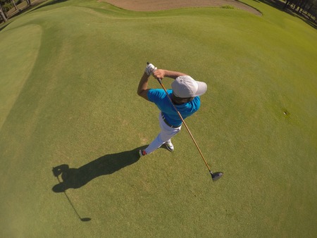 top view of golf player hitting shot with club on course at beautiful morningの写真素材