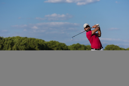 golf player hitting shot with driver on course at beautiful sunny dayの写真素材
