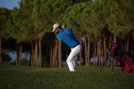 golfer shot ball from sand bunker at golf course with beautiful sunset in backgroundの写真素材