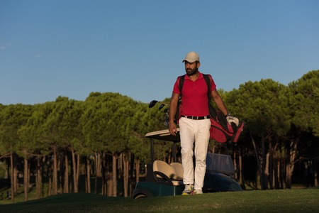 handsome middle eastern golfer  carrying  golf bag  and walking at course to next holeの写真素材