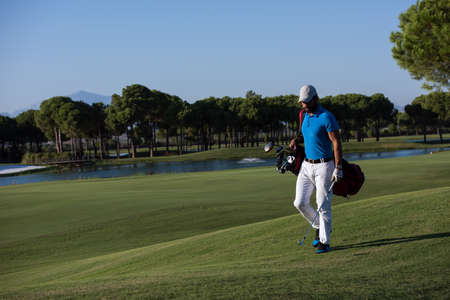 handsome middle eastern golf player carrying  bag  and walking at course to next holeの写真素材