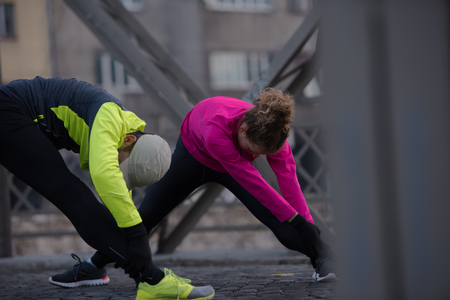 jogging couple warming up and stretching before morning running in the cityの写真素材