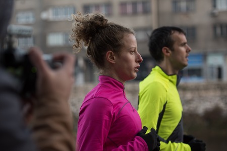 healthy young  couple jogging in the city  at early morning with sunrise in backgroundの写真素材