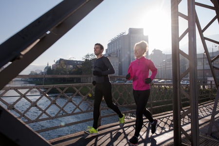 healthy young  couple jogging in the city  at early morning with sunrise in background