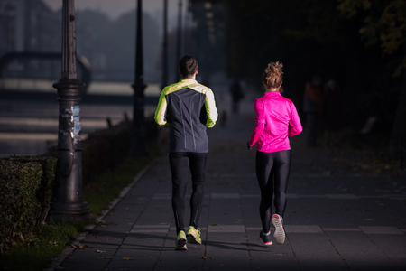healthy young  couple jogging in the city  at early morning with sunrise in backgroundの写真素材