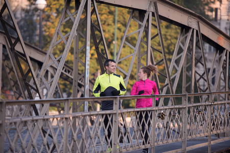 healthy young  couple jogging in the city  at early morning with sunrise in backgroundの写真素材