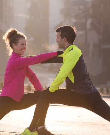jogging couple warming up and stretching before morning running in the cityの写真素材