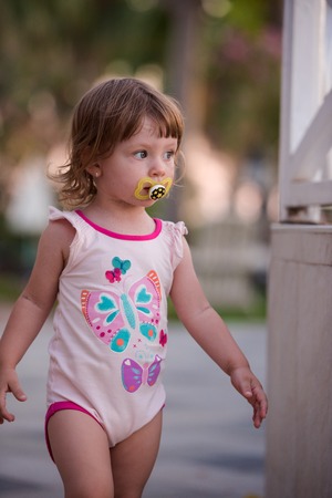cute baby girl walking from the beach at beautiful sunset in background