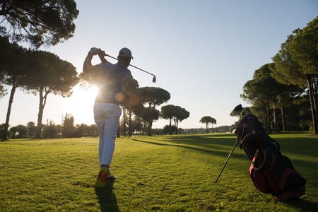 golf player hitting shot with driver on course at beautiful sunny dayの写真素材