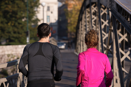 healthy young  couple jogging in the city  at early morning with sunrise in backgroundの写真素材