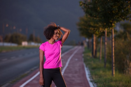 portrait of a young African American girl to run beautiful summer evening on city streetsの写真素材