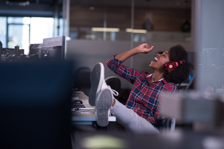 portrait of a young successful African American beautiful woman who enjoys spending a quality and joyful time while working in a large modern officeの写真素材