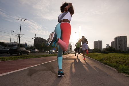 multiethnic group of young people on the jogging beautiful morning as the sun rises in the streets...